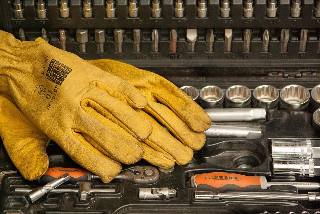 Yellow leather work gloves resting on a socket set