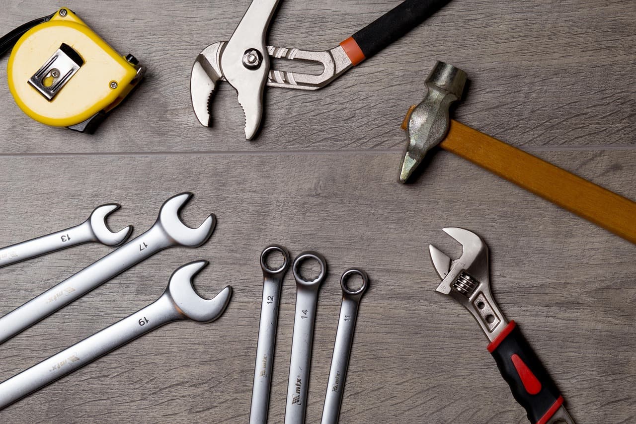 Spanners, a hammer, pliers and a tape measure on a wooden bench