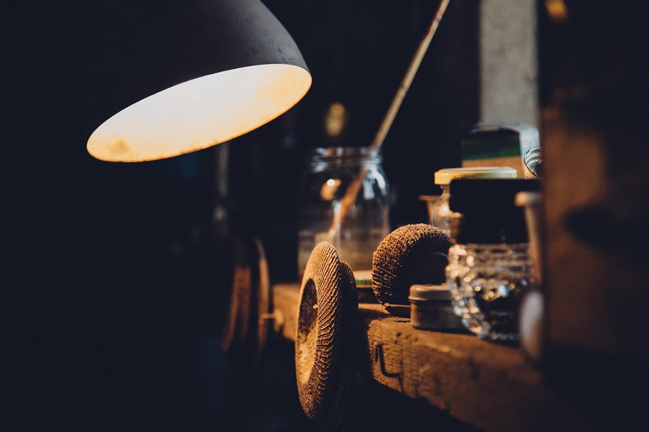 A lamp lighting a workbench in a dark workshop
